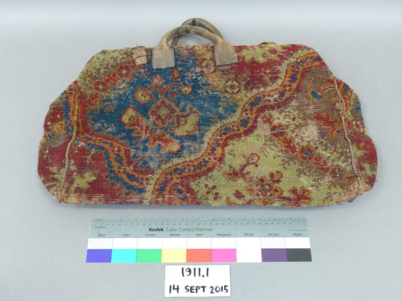 Object 1911 1 Bag made of multi coloured carpet like material with leather handles and straps